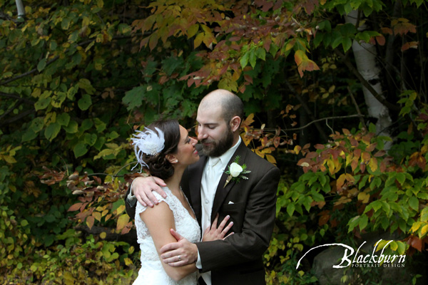Wishing Well Fall Wedding Bride and Groom Embracing in front of foliage